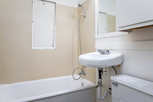 A white sink is mounted on a pipe in a bathroom.