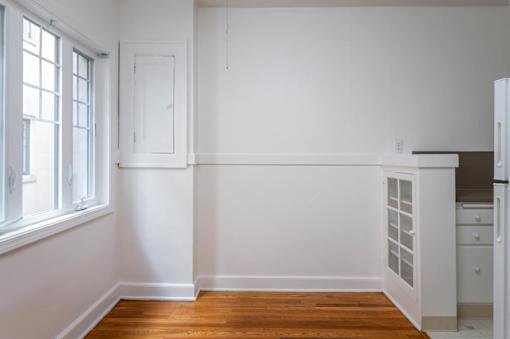 A kitchen with white cabinets and a wooden floor.