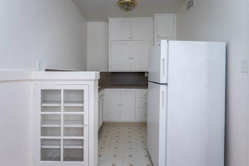 A kitchen with white cabinets and a white refrigerator.
