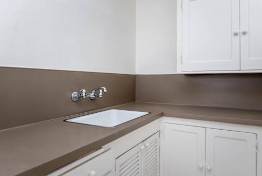 A kitchen with brown countertops and white cabinets.