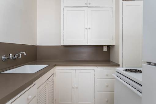 A kitchen with white cabinets and a stove top oven.