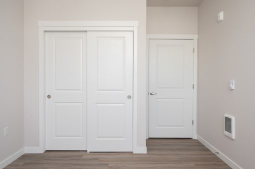 a pair of white doors in an empty room with a hardwood floor