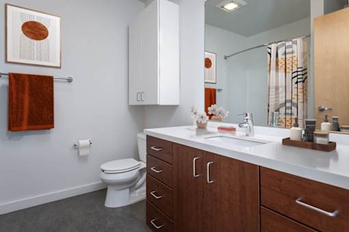 A bathroom with a toilet, sink, and cabinets.