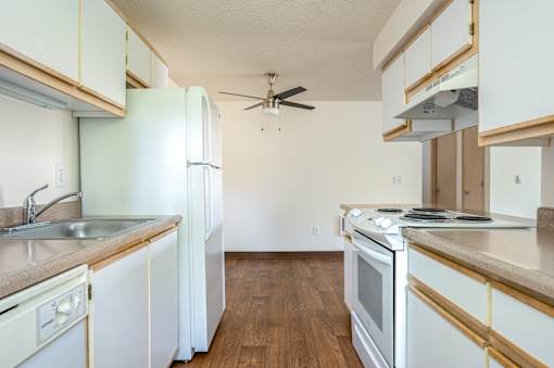 A kitchen with white appliances and wooden cabinets.