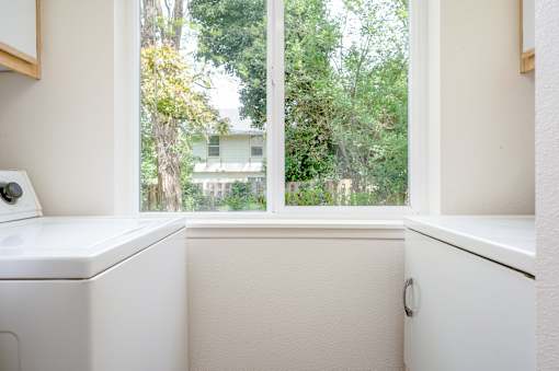 A white sink in a bathroom with a window overlooking a green area.