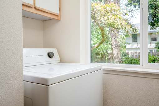 A white washing machine sits in a small laundry room.