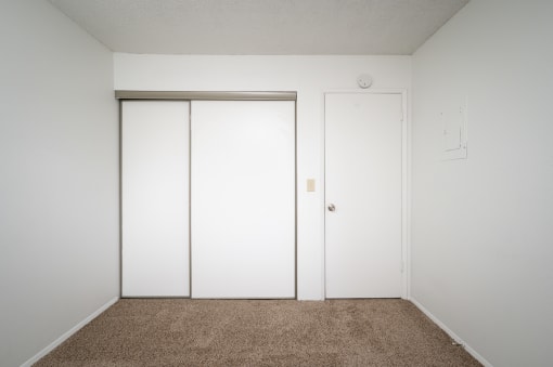 an empty room with white walls and white closet doors