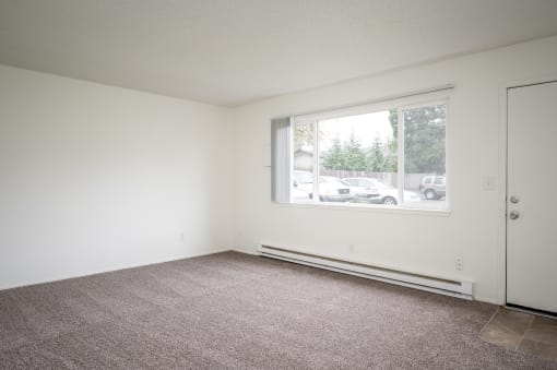 an empty living room with a large window and carpet