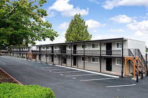 A parking lot in front of a building with a balcony.
