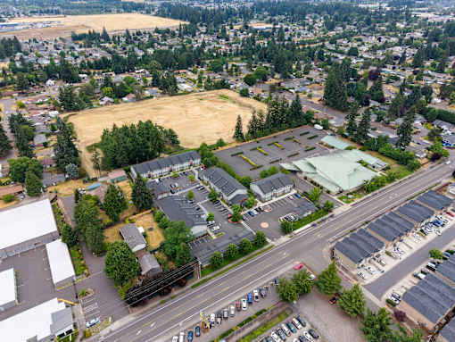 A parking lot is surrounded by trees and buildings.