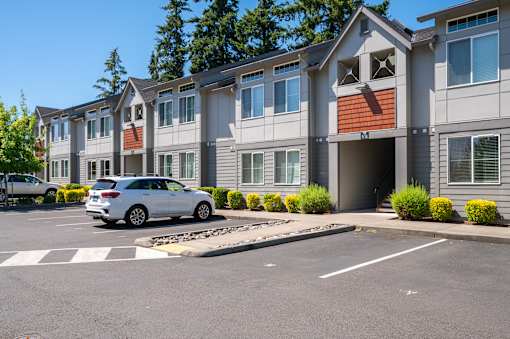 A white car is parked in a parking lot in front of a building.