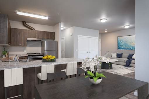 A modern kitchen with a dark countertop and a dining area with a painting on the wall.