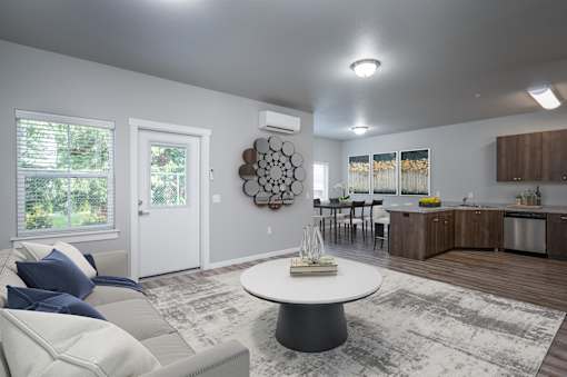A modern living room with a white couch and a round table in the center.