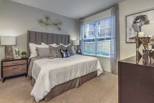 A bedroom with a large bed and a nightstand with a plant on it at Crabtree Lakeside Apartments, Raleigh, NC, 27612