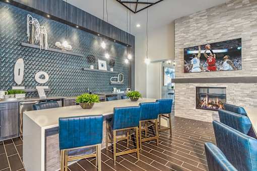 A modern kitchen with blue chairs and a fireplace at Crabtree Lakeside Apartments, Raleigh, NC, 27612