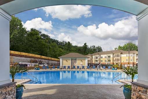 A large swimming pool surrounded by a stone wall and a white pillar at Crabtree Lakeside Apartments, North Carolina