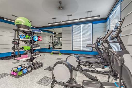 A gym with a row of treadmills and exercise equipment at Crabtree Lakeside Apartments, Raleigh