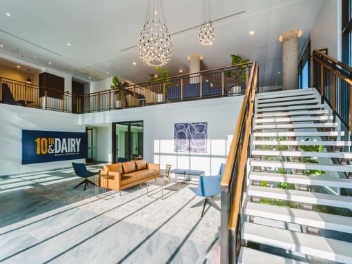 a lobby with a staircase and a couch and chairs