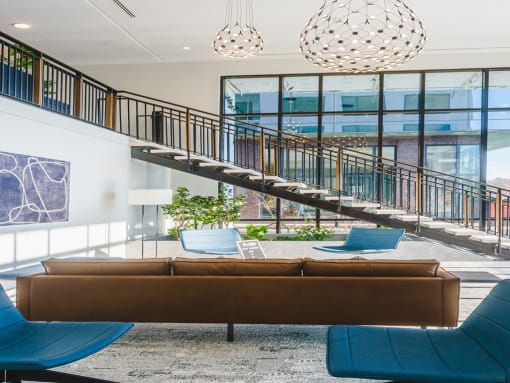 a living room with a staircase and a couch and chairs
