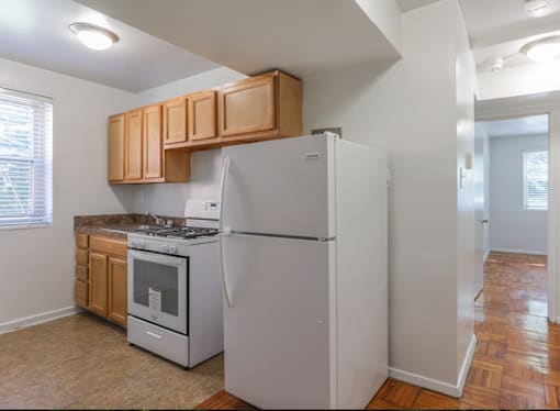 A kitchen with a white refrigerator and wooden cabinets.