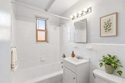 A white bathroom with a window in the shower.