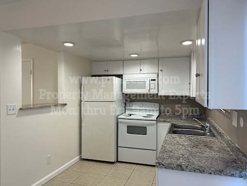 A kitchen with white appliances and a granite countertop.