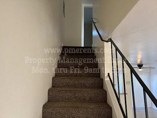 A staircase with a carpeted runner and a metal railing.