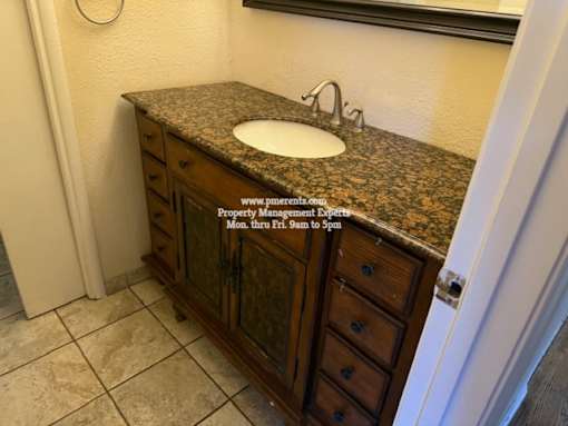 A bathroom with a granite countertop and a sink.