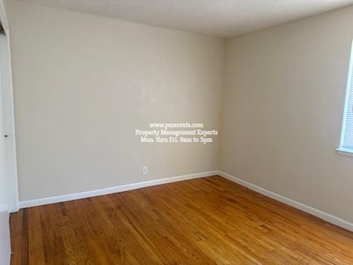 A room with wooden floors and a wall with a website address written on it.