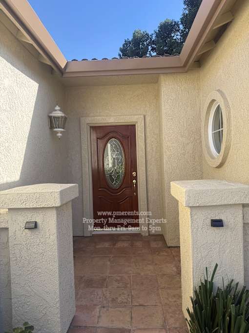 A house entrance with a brown door and a window above it.
