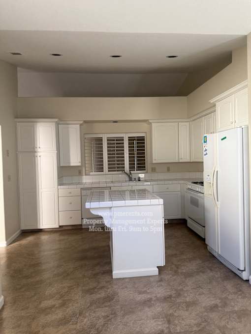A kitchen with white appliances and cabinets.