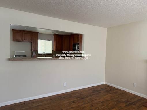 A room with wooden floors and a wall with a mirror and a sign that says "www.propertymanagement.com".