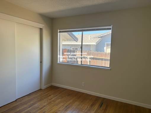 A room with a window showing a view of a house and a fence.