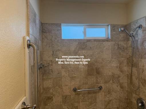 A tiled shower with a window above it.
