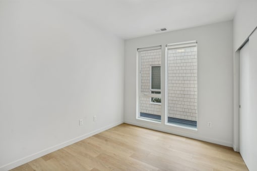 a living room with white walls and a large window with blinds