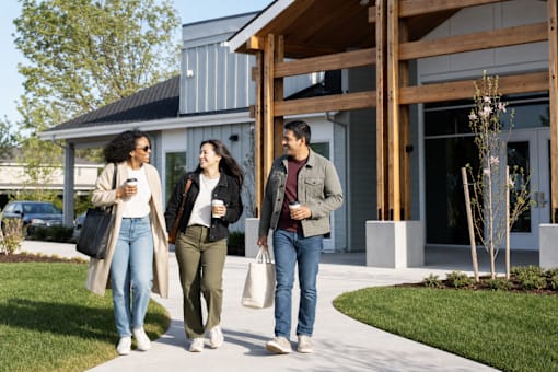Three people walking in front of a modern building.