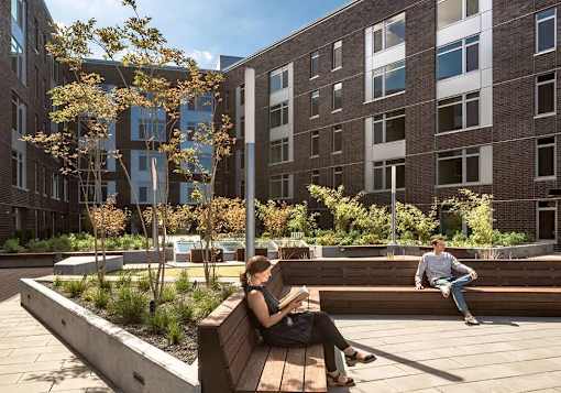 Person sitting reading on bench in sunlit courtyard