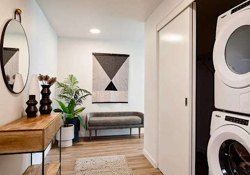 Entry foyer with washer and dryer in a closet with small bench and table and mirror