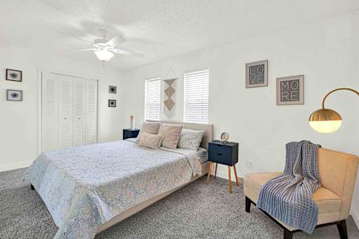 A bedroom with a bed, chair, and pictures on the wall.