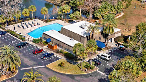 A large building with a pool and a parking lot in front.