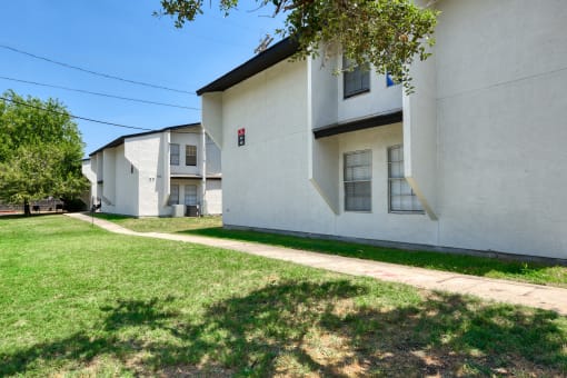 a white building with a sidewalk in front of it and some other houses