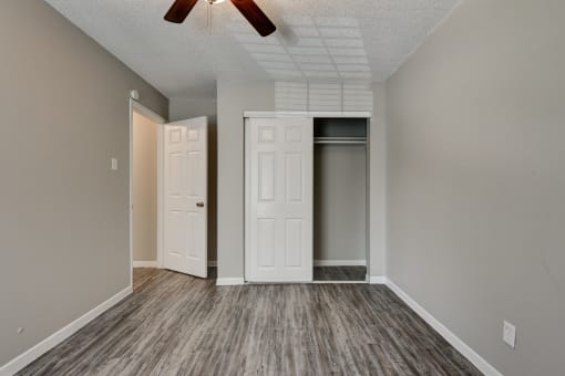 an empty living room with a closet and a ceiling fan