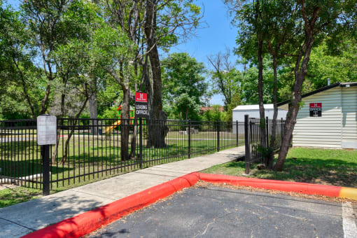 the entrance to a park with a fence and a red curb