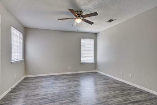 an empty living room with a ceiling fan and window