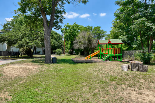 a playground in a park with trees and a swing set