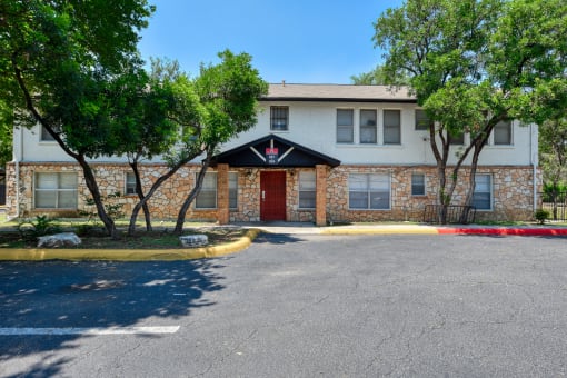 a brick building with a red door and trees in front of it