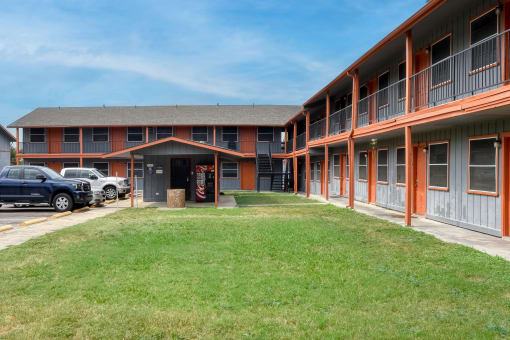 an exterior view of a building with a lawn and a parking lot at The Crossings at Montrose Apartments, Texas