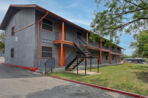 the exterior of an apartment building with stairs and a sidewalk at The Crossings at Montrose Apartments, San Antonio, Texas