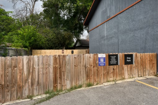 a wooden fence with signs on it in front of a building at The Crossings at Montrose Apartments, Texas