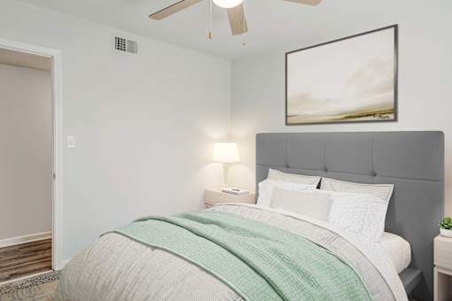 A bedroom with a bed, a lamp, and a painting on the wall.